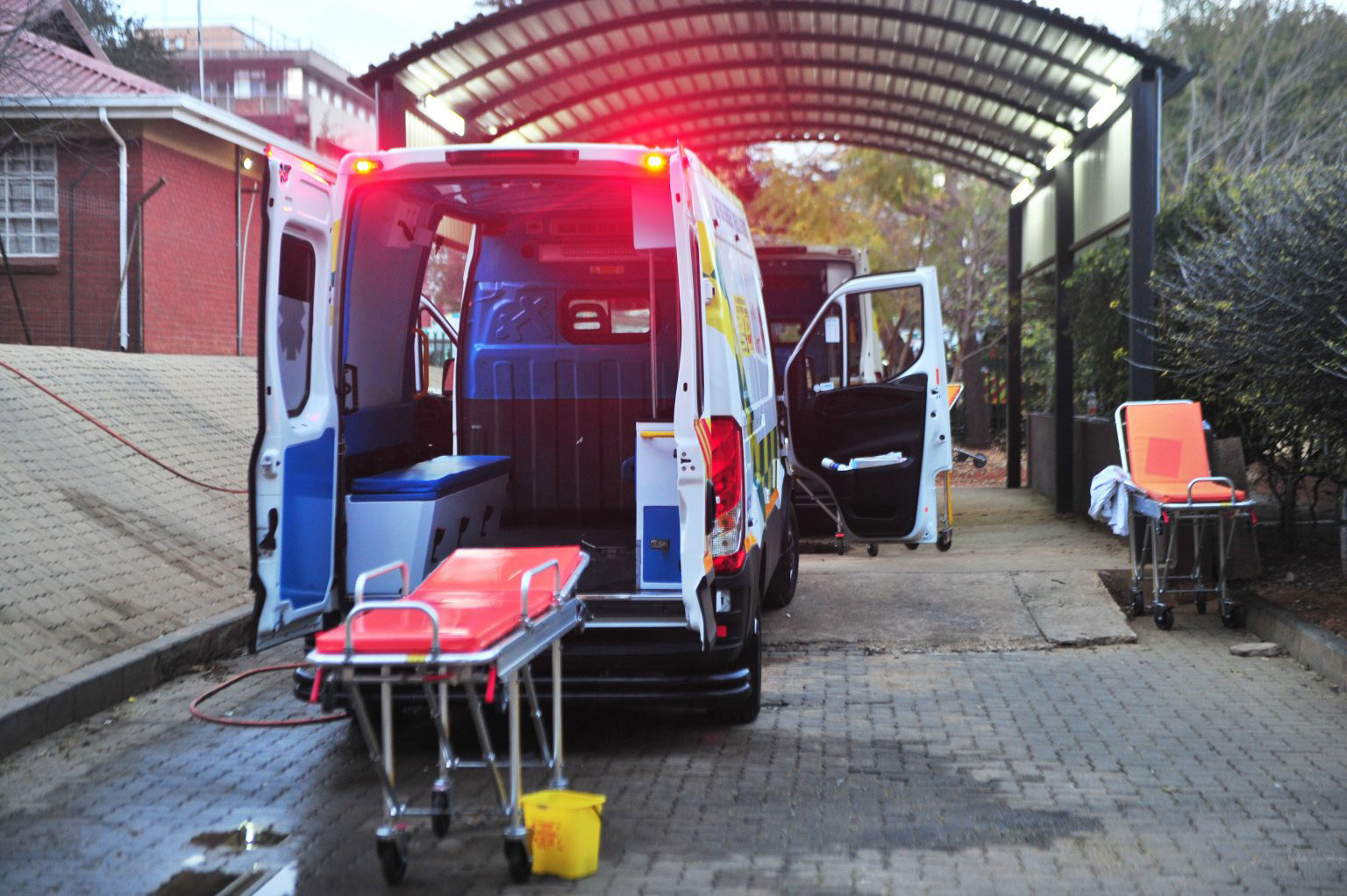 An empty ambulance with its back doors open parked outside a hospital