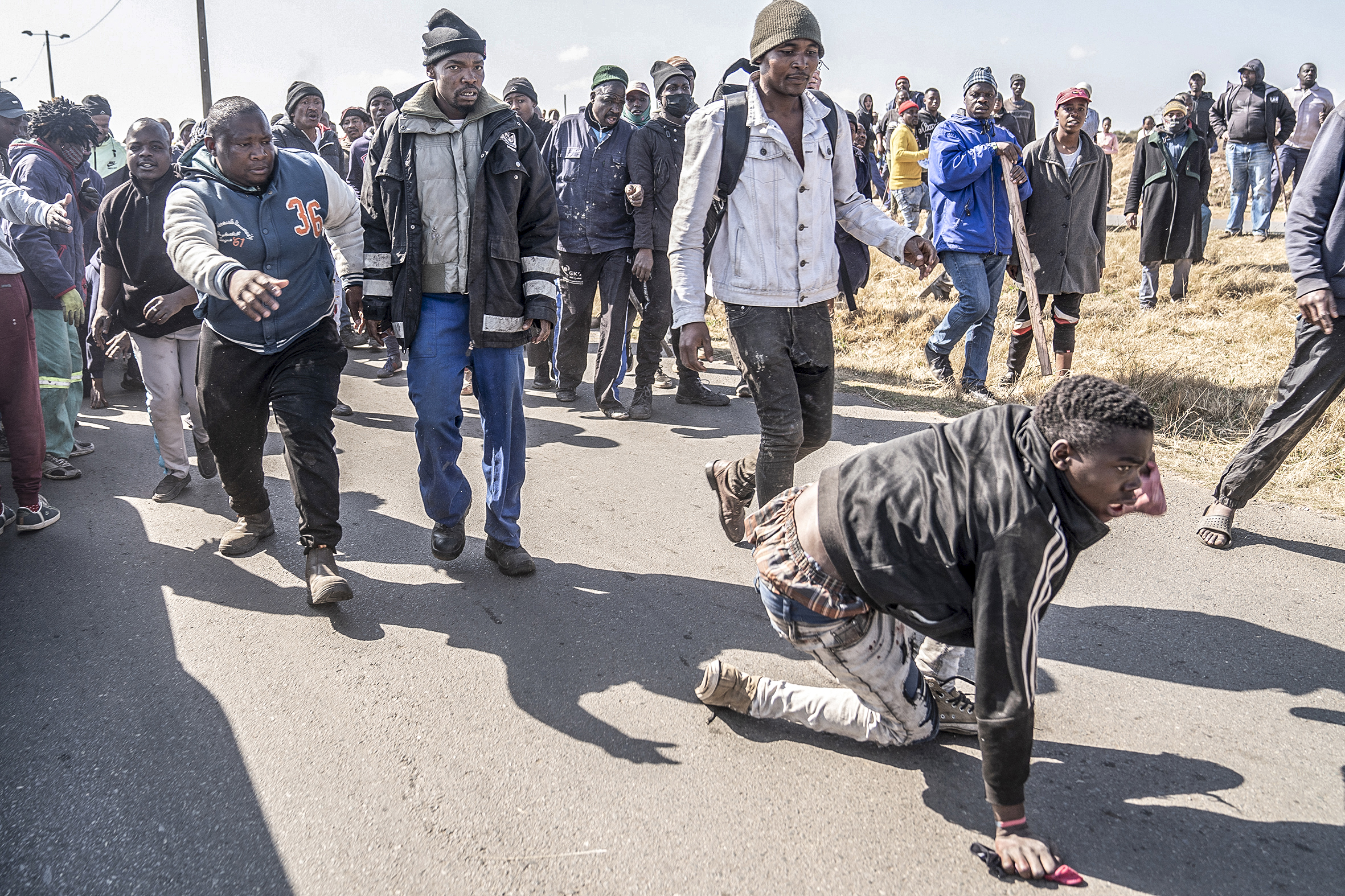 An alleged zama zama crawls on the ground after being captured by residents.