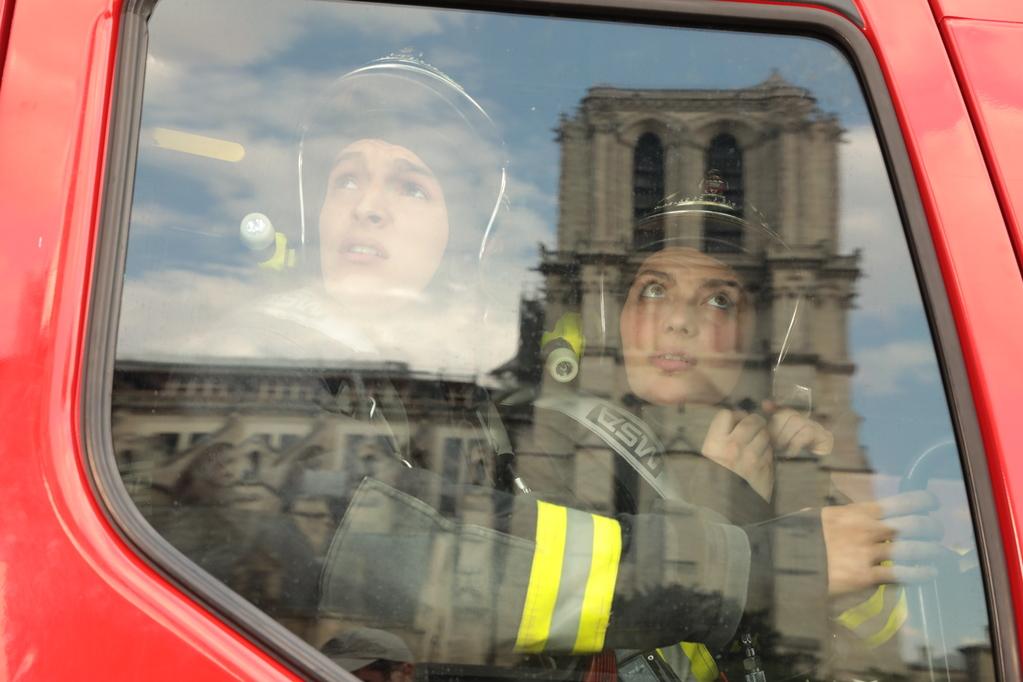 Firefighters look out of their truck at the Notre-Dame, reflected in their vehicle window. Production still from 'Notre-Dame On Fire'. Image: courtesy of Universal Studios