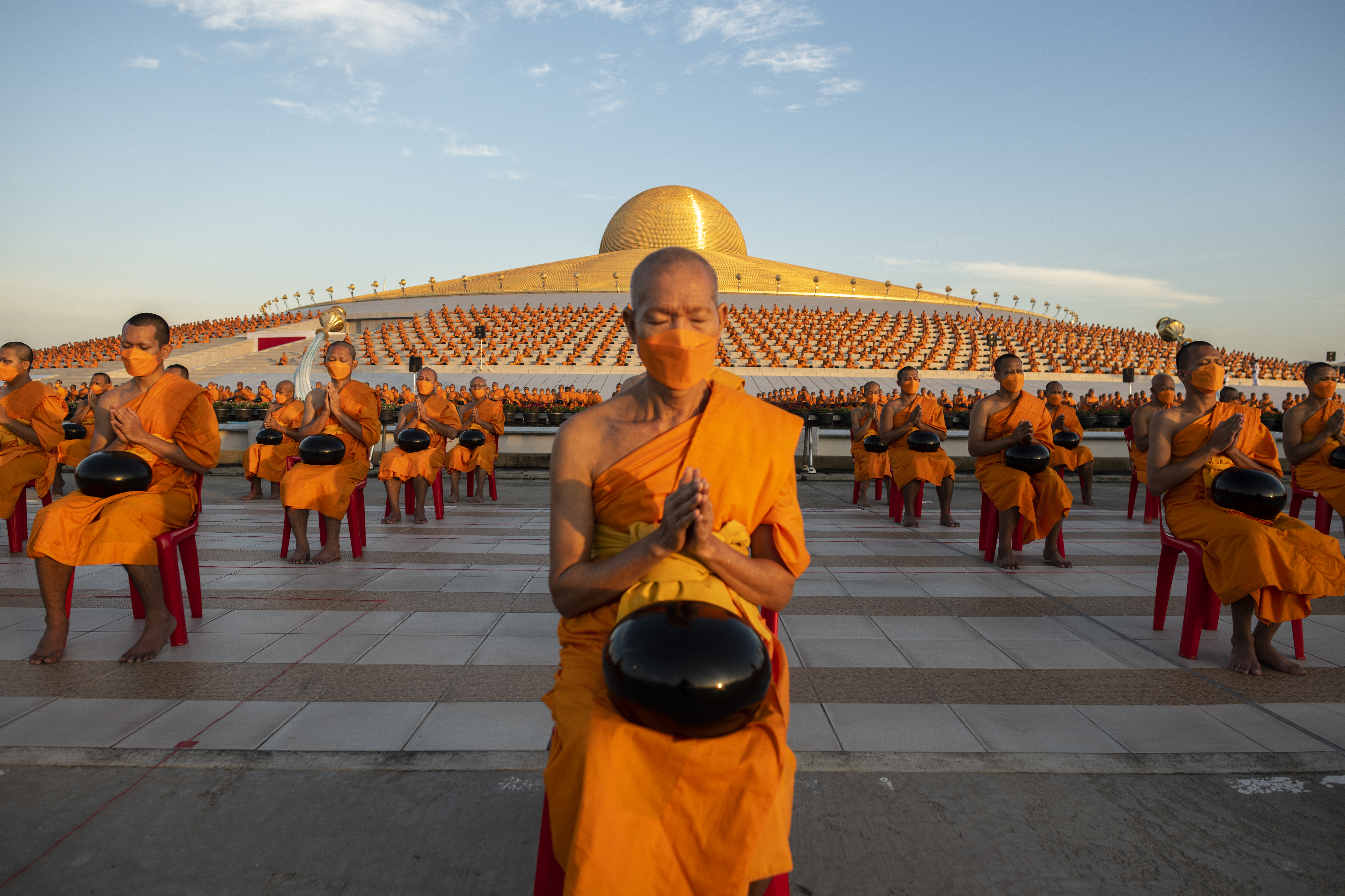 BANGKOK, THAILAND - JANUARY 01: Buddhist monks pray during the mass alms giving ceremony for New Year where 3,000 monks attend at Wat Phra Dhammakaya Buddhist Temple on January 01, 2023 in Pathum Thani, Thailand. Alms giving ceremony is commonly practiced by Thai Buddhists during New Year. It has been three years since Wat Phra Dhammakaya Buddhist Temple last organized a mass alms giving ceremony due to the pandemic. (Photo by Sirachai Arunrugstichai/Getty Images)