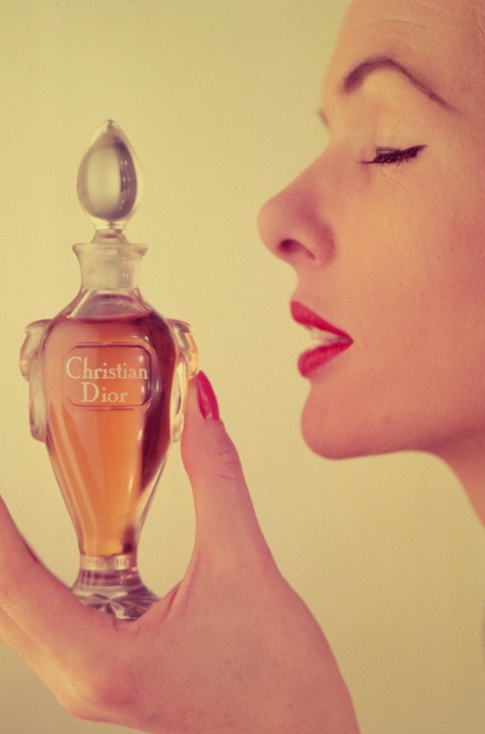 A woman holding a bottle of Miss Dior perfume by Christian Dior, December 1954. The half ounce flagon is presented in a Baccarat crystal bottle, and costs 6 pounds, 19 shillings. (Photo by Housewife/Getty Images)