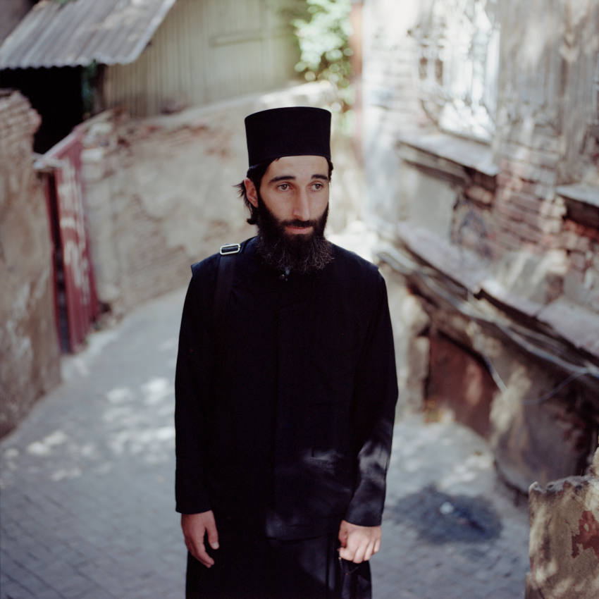 'Yuri, Tbilisi, Georgia, 2022.' I first saw Yuri, he seemed to be floating above the crowd in the busy streets of Dzveli Tbilisi. He was on his way to mass and his height and dark clothes made him stand out – it seemed like you could not take your eyes off him. I remembered Yuri some time later, when I was on my way to Omalo and suddenly saw some lonely crosses hovering with the same dignity in the mist of the Caucasus mountain pass. © Tadas Kazakevicius, Lithuania, Shortlist, Professional competition, Portfolio, Sony World Photography Awards 2023