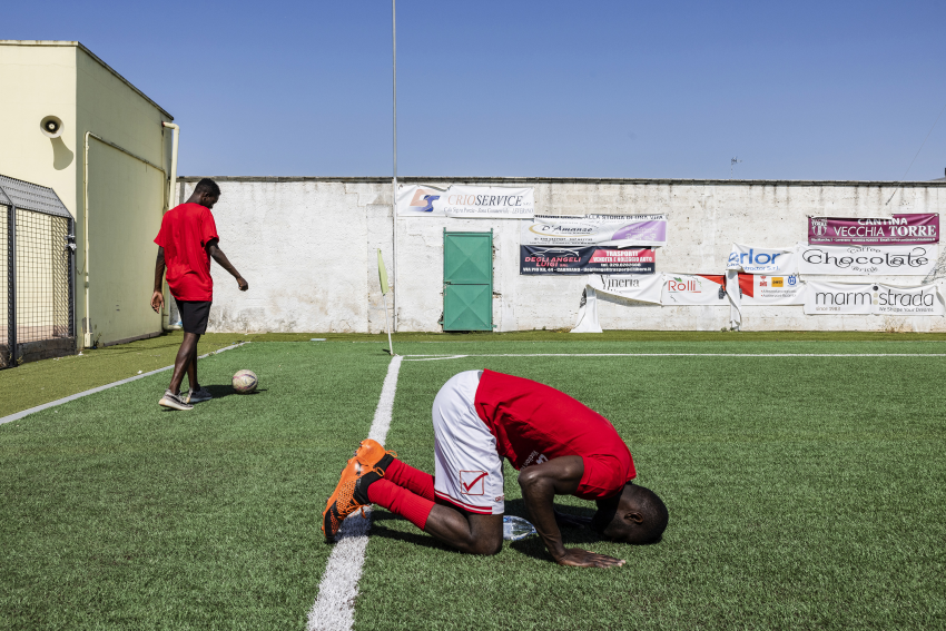 An ASD Rinascita (Rebirth) Refugees player kisses the playing field before the start of the play-off final match. Leverano, Lecce, Italy, 22 May 2022 Every year, thousands of children leave West Africa with dreams of becoming professional footballers in Europe, but few of them make it. Many of them are approached by fake football agents who promise trials at international football clubs, but when they get to Europe they are often exploited in labour camps between Spain and Portugal, and sometimes abandoned on the street without their documents. In Carmiano in southern Italy, a town of 15,000 inhabitants, there is a young football team – the ‘Rinascita Refugees’ – which is made up of asylum seekers. The team belongs to a project aimed at protecting unaccompanied foreign minors, and for a number of years it has been at the top of the championship tables in the Puglia region. Guineans, Senegalese, Gambians, Nigerians and Malians are among the nationalities of young footballers whose kit bears the motto: ‘Let’s kick racism’. © Giuseppe Carotenuto, Italy, Shortlist, Professional competition, Sport, Sony World Photography Awards 2023 